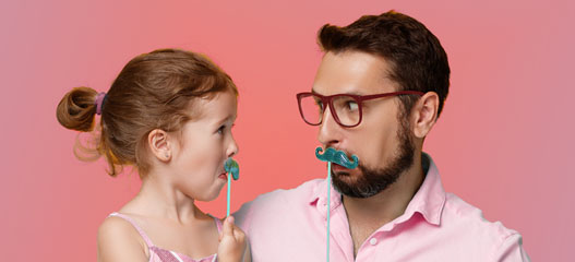 padre e hija haciendo caras divertidas con bigotes de papel